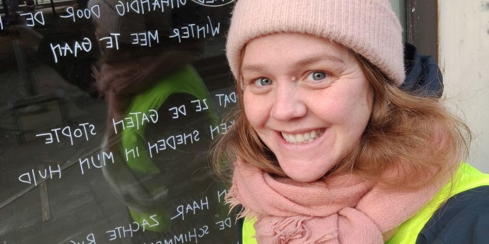 Sanne Van Herck brengt een Weesgedicht aan op een raam